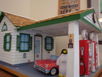 Pierre with Toy Car at Miniature Gas Station by Lindsay Gladstone